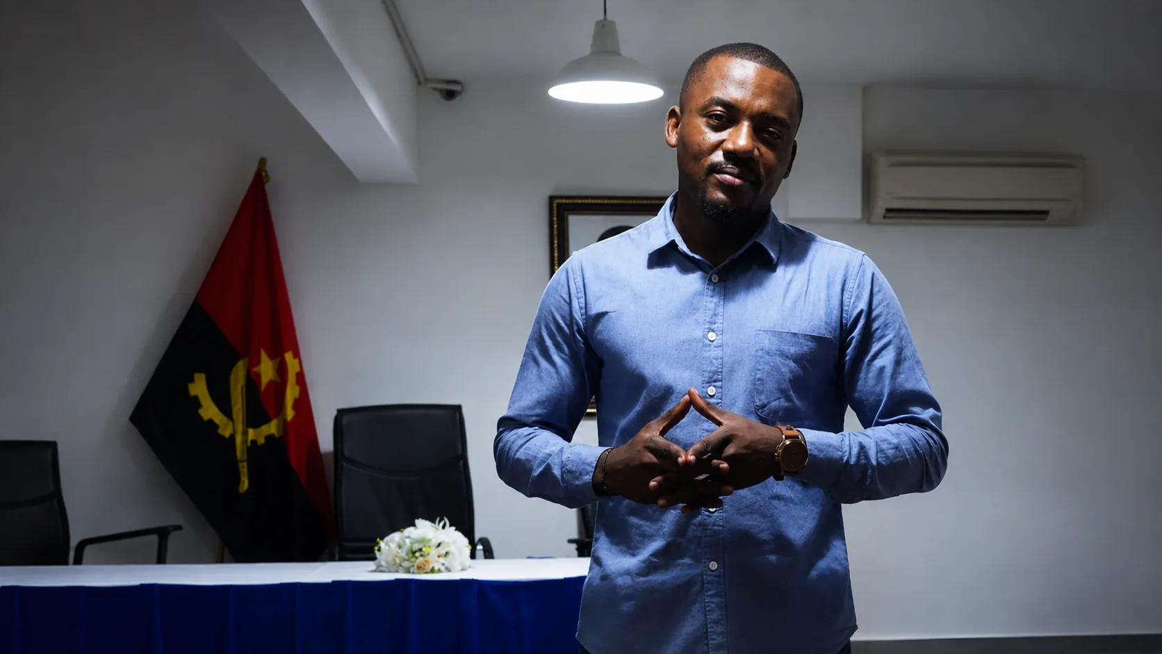 Smith a falar numa sala com a bandeira de Angola
